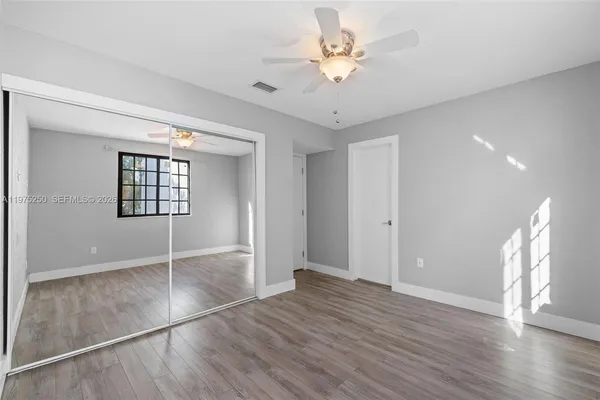 an empty room with wooden floor and ceiling fan