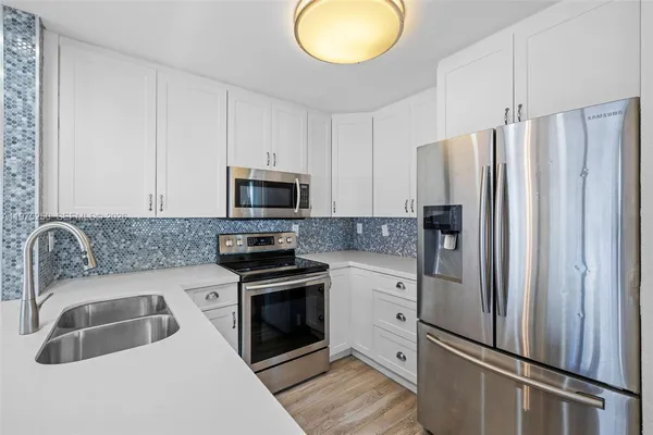 a kitchen with stainless steel appliances granite countertop a refrigerator sink and stove