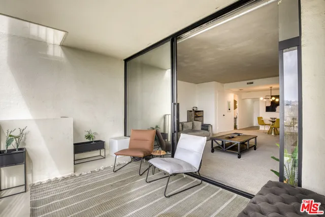 a living room with couches chairs and kitchen view with wooden floor