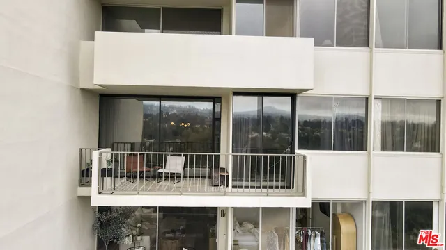 a view of a white house with a floor to ceiling window and a small yard