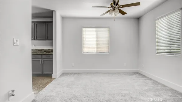 an empty room with chandelier fan and windows