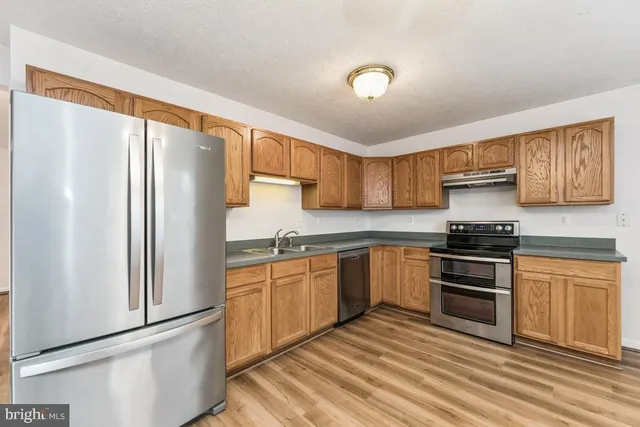 a kitchen with stainless steel appliances granite countertop a refrigerator stove top oven and sink