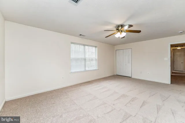 an empty room with windows and chandelier fan