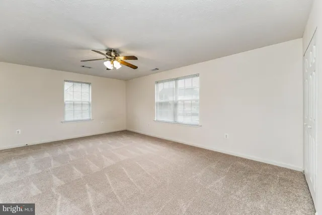 an empty room with windows and ceiling fan