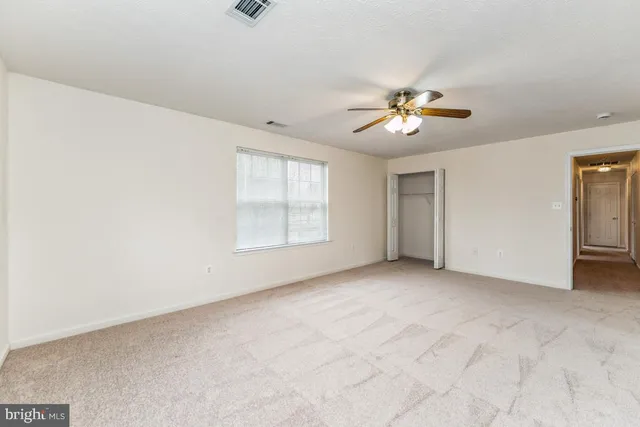an empty room with chandelier fan and windows