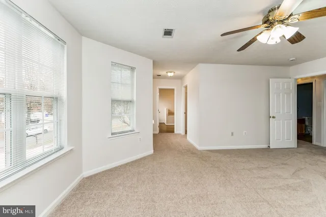 a view of an empty room with window and chandelier fan