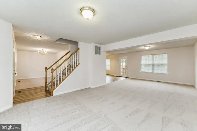 a view of an empty room with stairs and a window