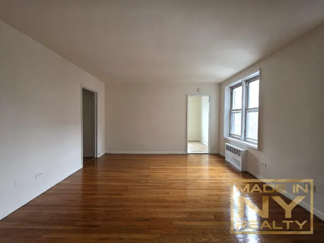 a view of an empty room with window and wooden floor