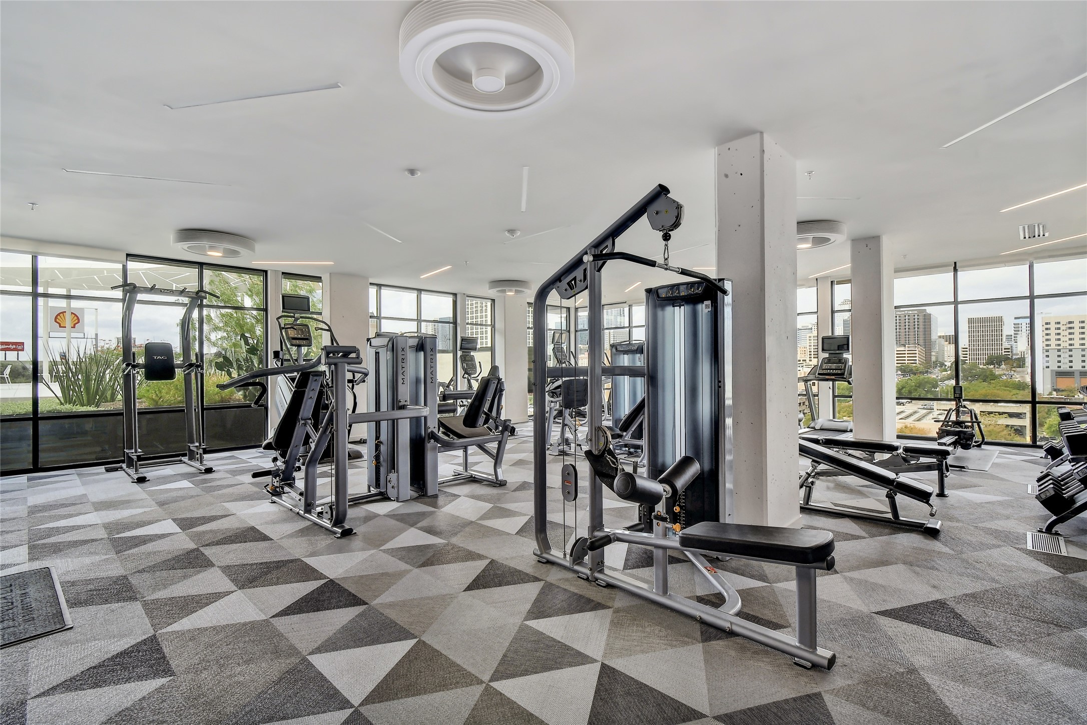 800 Embassy Drive, Unit 602 Austin, TX 78702 - Photo 26 of 37 Spacious fitness area featuring extensive floor-to-ceiling windows, modern geometric carpet, ceiling-mounted lighting, and structural columns