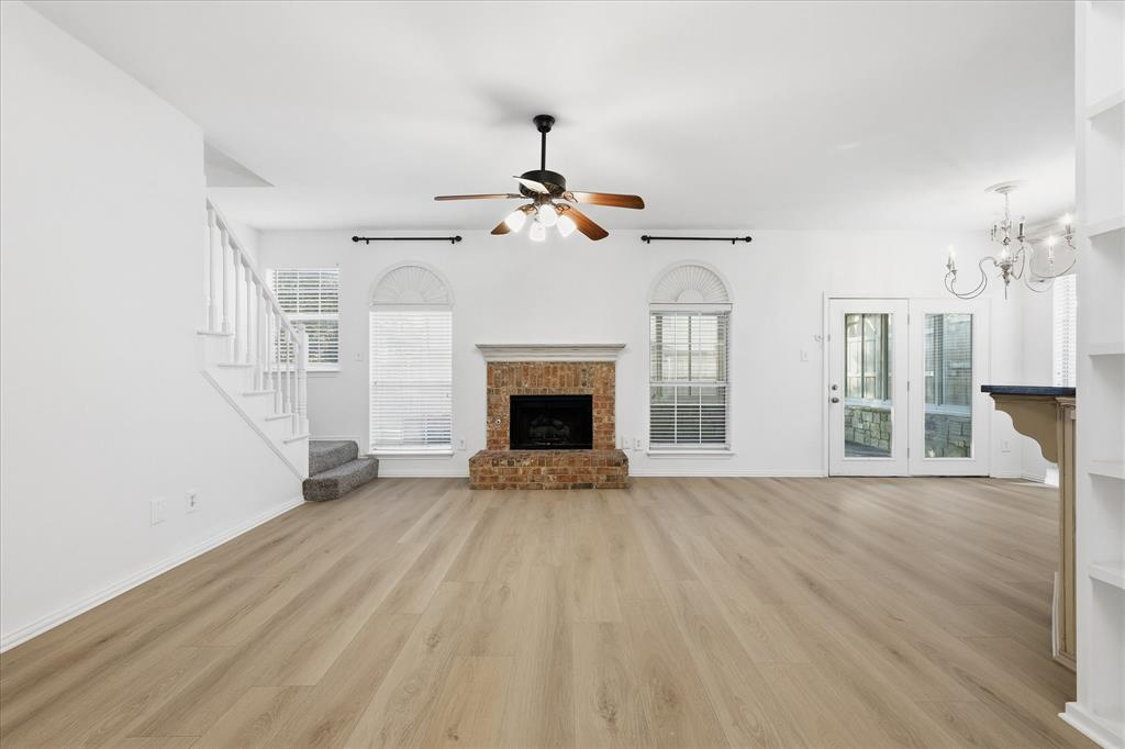 5023 Falcon Hollow Road McKinney, TX 75072 - Photo 8 of 25 Unfurnished living room featuring a fireplace, light wood-style floors, ceiling fan, and suspended lighting