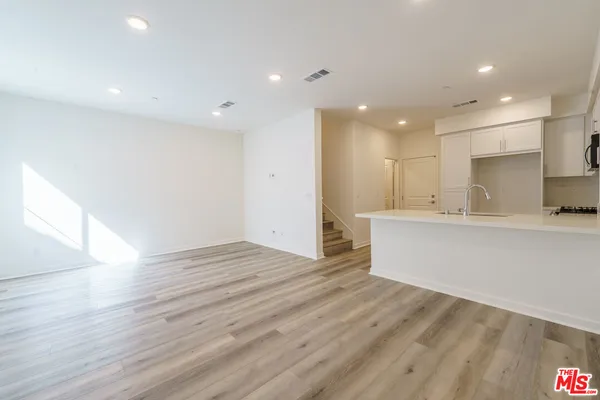 a view of kitchen with kitchen island a sink wooden floor and a refrigerator