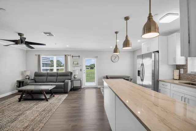 a living room with furniture kitchen view and a wooden floor