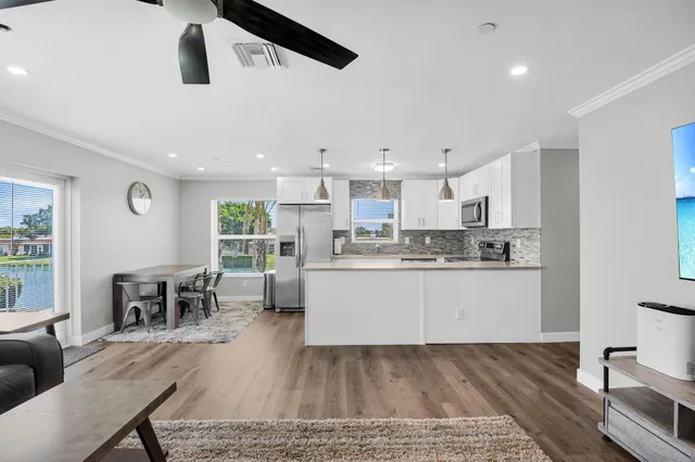 a kitchen with stainless steel appliances granite countertop a stove top oven a sink a dining table and chairs with wooden floor