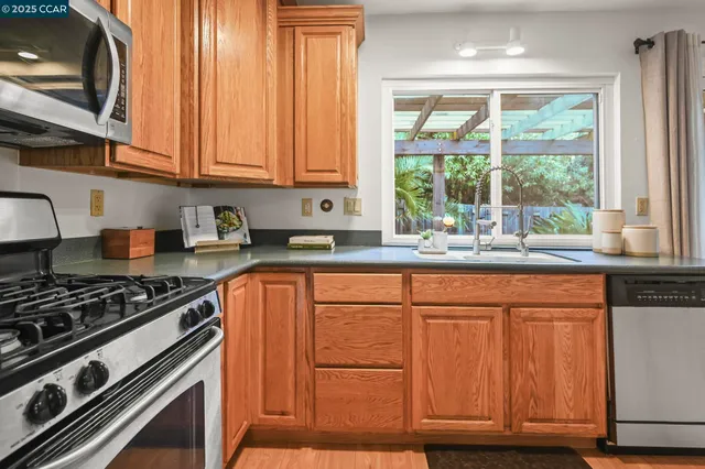 a kitchen with stainless steel appliances granite countertop a stove a sink and a microwave