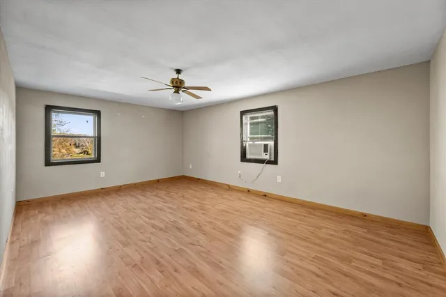 a view of an empty room with window and wooden floor