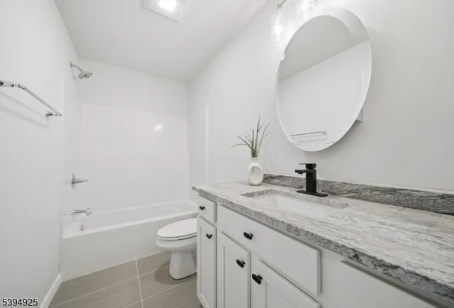 a bathroom with a granite countertop toilet a sink and a mirror