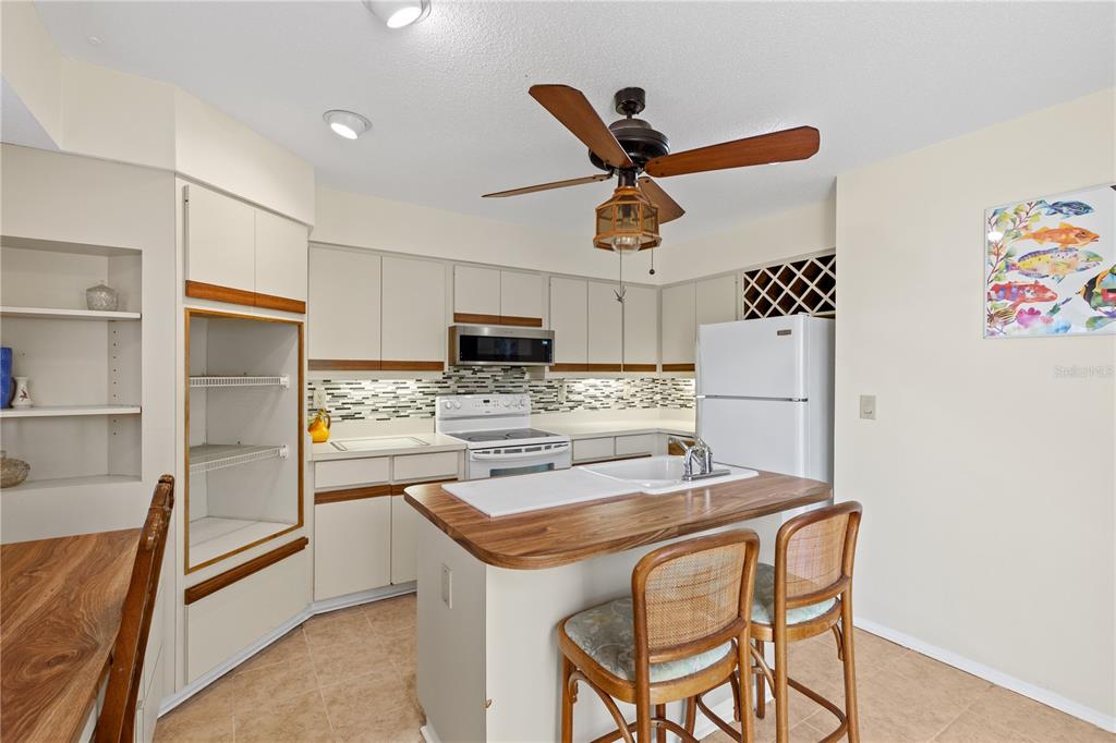 1315 Pine Needle Road Venice, FL 34285 - Photo 7 of 52 a kitchen with stainless steel appliances kitchen island granite countertop a refrigerator and a stove top oven