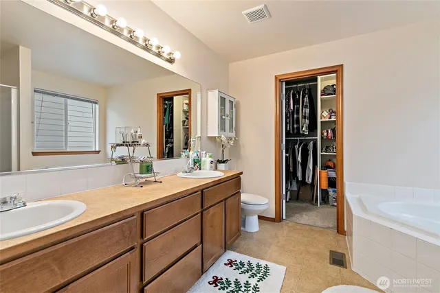 a spacious bathroom with a tub double sink and a mirror