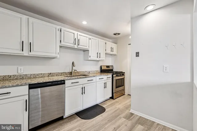 a kitchen with stainless steel appliances granite countertop a stove and white cabinets