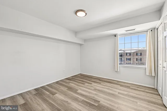 a view of empty room with window and wooden floor
