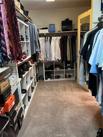 a view of walk in closet with clothes and shoes