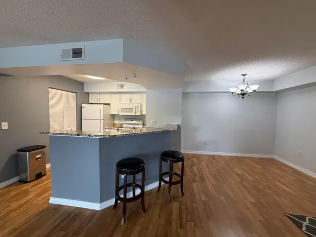 a kitchen with kitchen island stainless steel appliances a dining table chairs and wooden floor