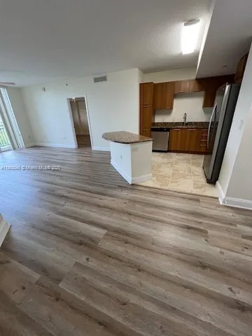 a view of kitchen with stainless steel appliances wooden floor