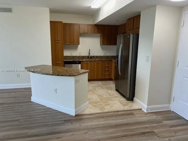 a kitchen with granite countertop a refrigerator and a sink