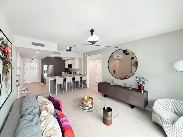 a living room with furniture a mirror and wooden floor