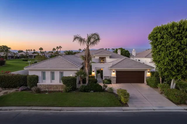 a front view of a house with a garden and tree