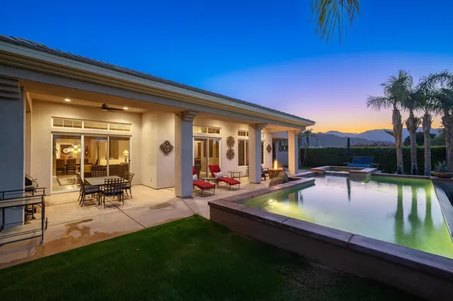 a view of swimming pool with outdoor seating and house in the background