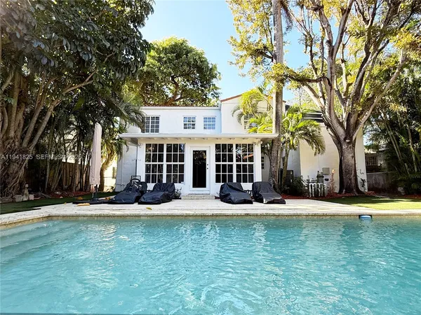 front view of a house with a swimming pool and porch with furniture