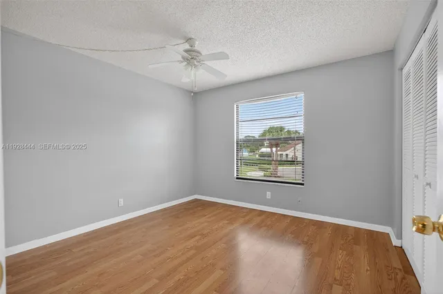 an empty room with wooden floor fan and windows