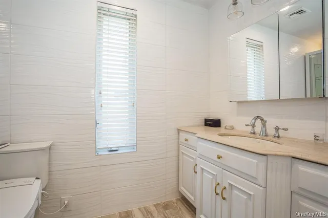 a bathroom with a granite countertop sink toilet and mirror