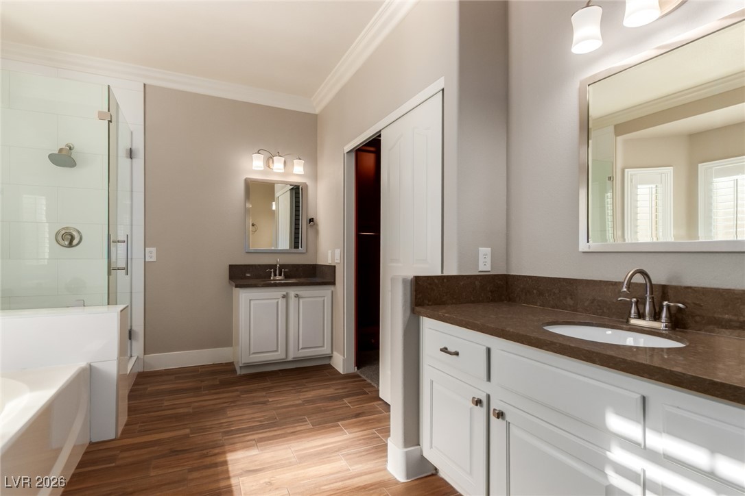 264 Pointe Ranier Avenue Henderson, NV 89012 - Photo 17 of 47 Full bathroom featuring crown molding, a bath, two vanities, light wood-type flooring, and a shower stall