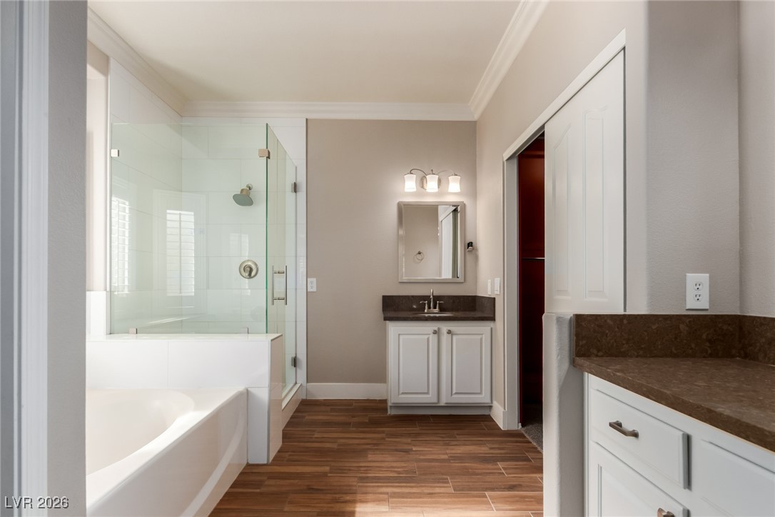 264 Pointe Ranier Avenue Henderson, NV 89012 - Photo 18 of 47 Bathroom featuring vanity, a garden tub, wood finish floors, a stall shower, and ornamental molding
