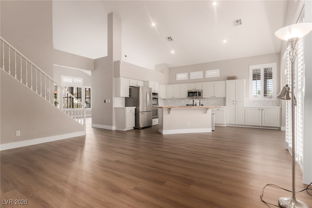 264 Pointe Ranier Avenue Henderson, NV 89012 - Photo 4 of 47 Unfurnished living room with dark wood-style flooring, stairs, a high ceiling, and plenty of natural light