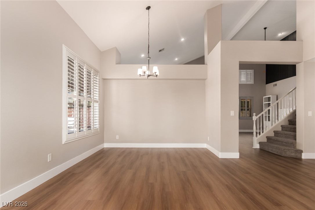 264 Pointe Ranier Avenue Henderson, NV 89012 - Photo 6 of 47 Unfurnished dining area with stairway, dark wood-style floors, high vaulted ceiling, a chandelier, and recessed lighting