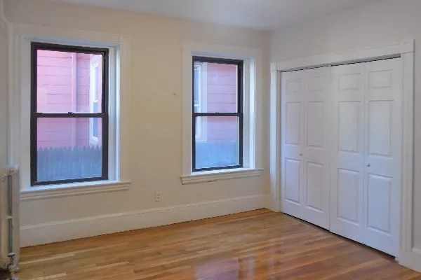 a view of an empty room with window and wooden floor