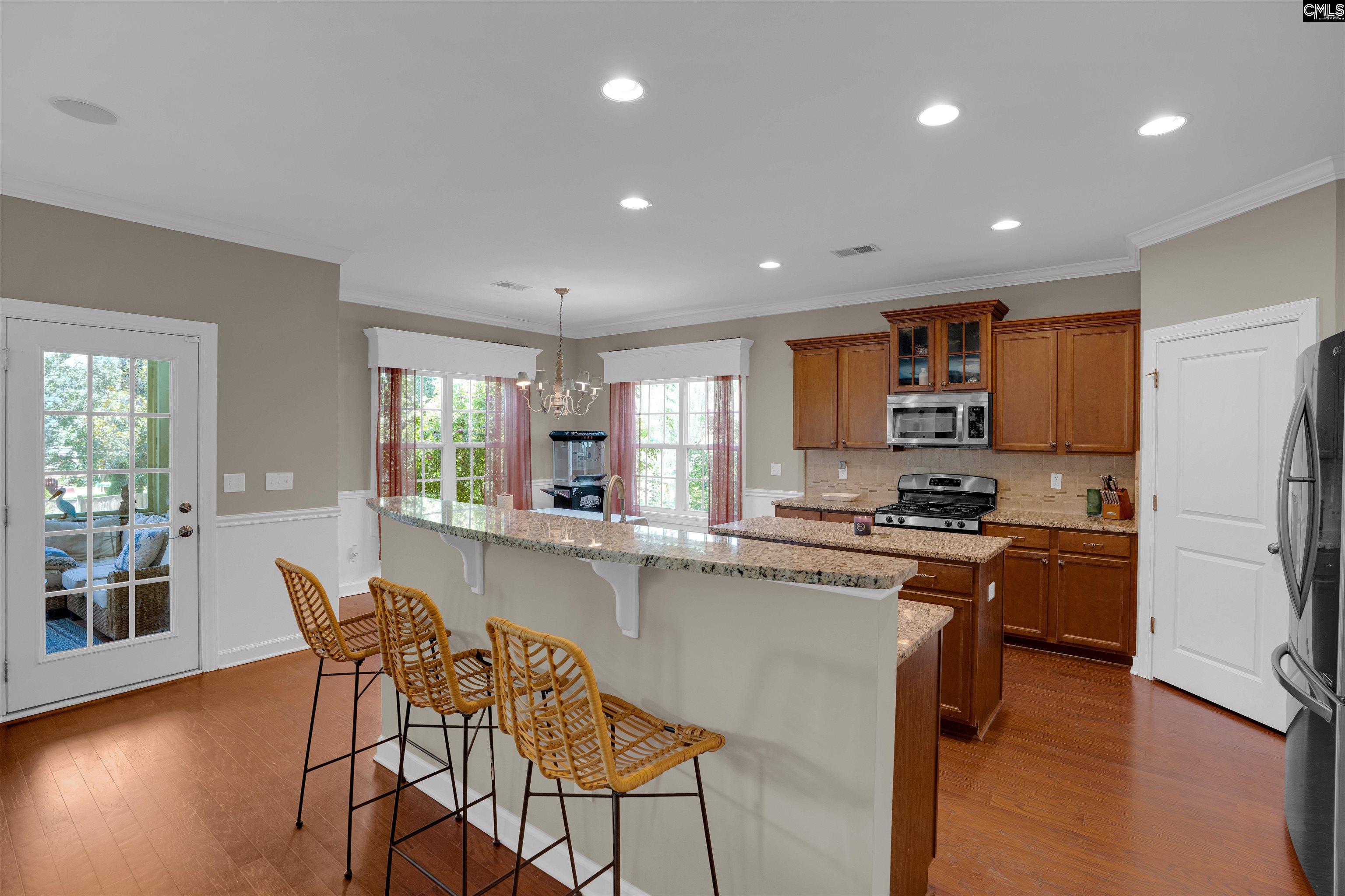 321 Asa Rose Lexington, SC 29072 - Photo 11 of 52 a kitchen with stainless steel appliances granite countertop a refrigerator a stove top oven a sink a dining table and chairs with wooden floor