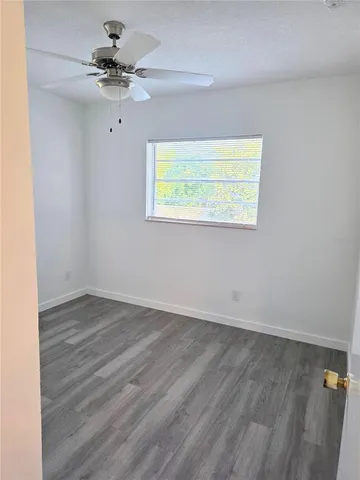 an empty room with a window and a ceiling fan