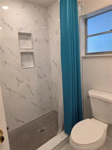 a white toilet sitting next to a shower curtain