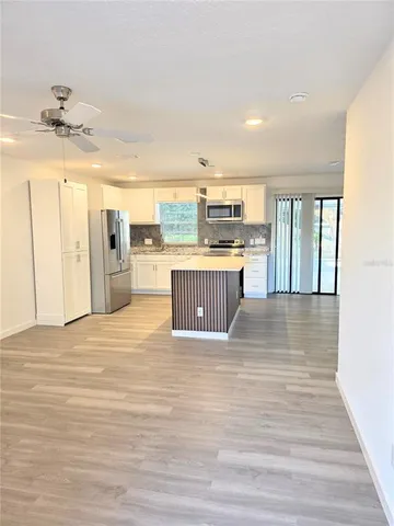 a view of a kitchen with kitchen island a sink wooden floor and a counter top space