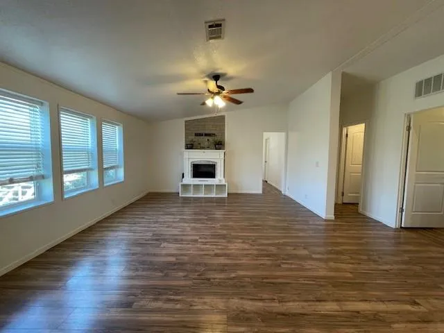 a view of an empty room with window and wooden floor