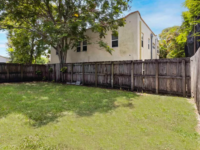a view of backyard with wooden fence and trees
