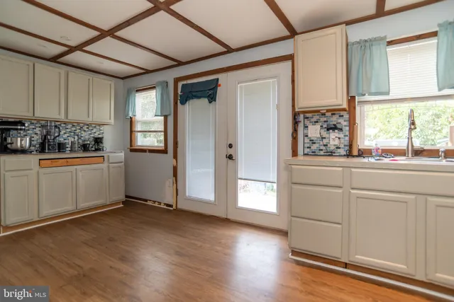 a kitchen with white cabinets and wooden floor
