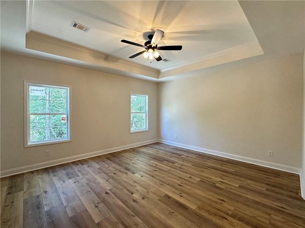 10 Lee Road Salem, AL 36874 - Photo 14 of 25 Tray ceiling with crown molding, ceiling fan, wood-finish flooring, and two windows