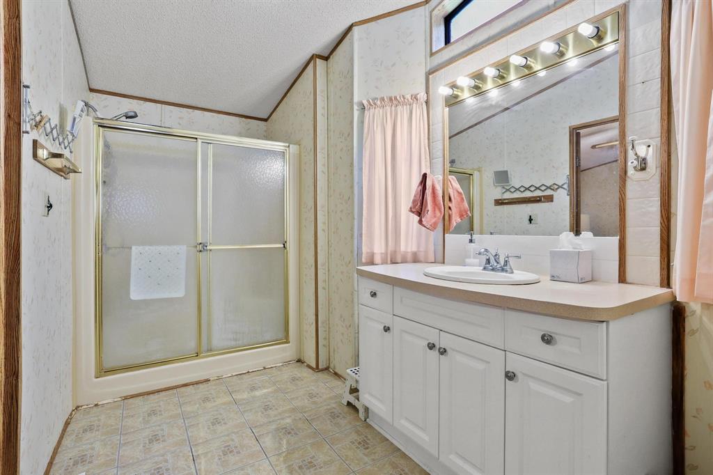 2496 Greer Road Sadler, TX 76264 - Photo 25 of 39 Bathroom featuring a single vanity with white cabinetry, a large mirror, and a shower with sliding glass doors
