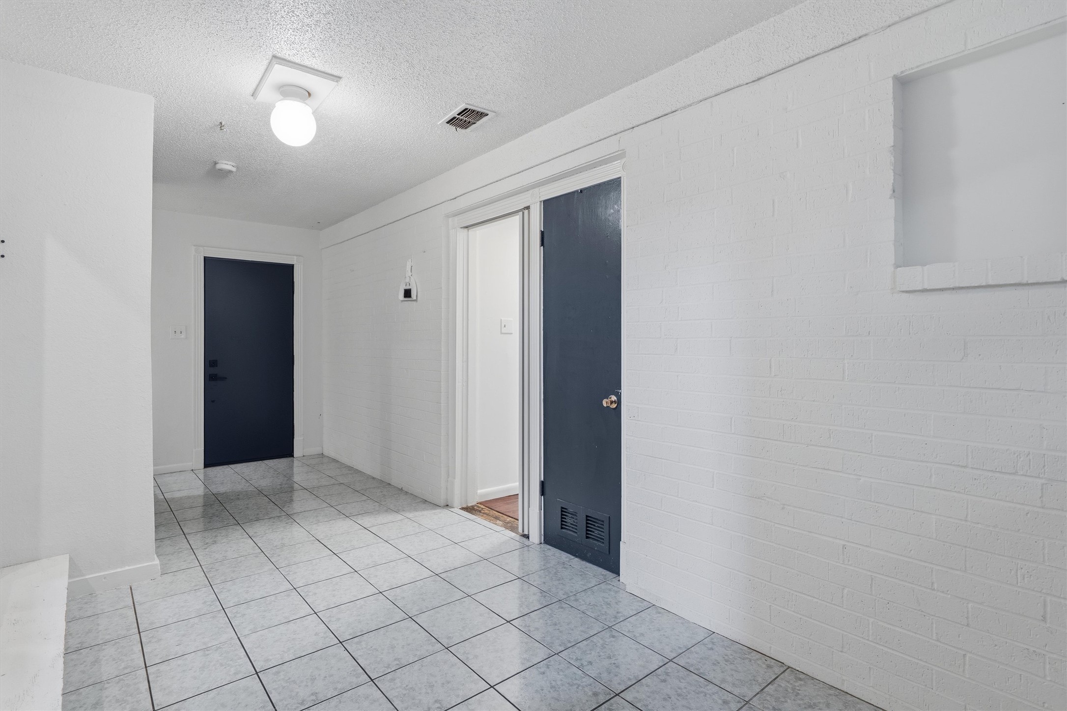2204 Santa Rita Street Austin, TX 78702 - Photo 16 of 23 Tiled flooring spans this long hallway under textured ceilings.