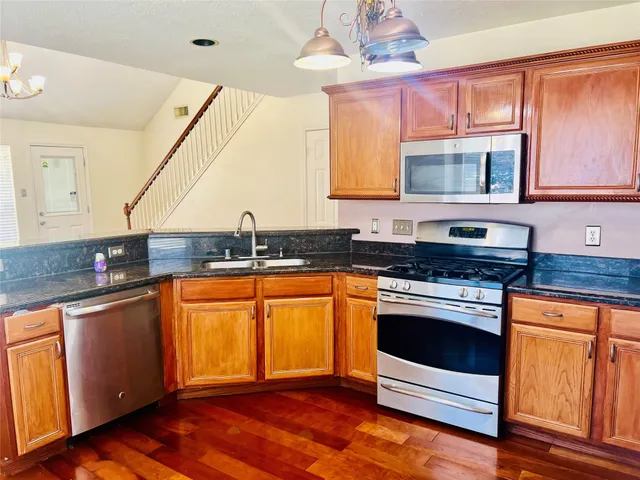 a kitchen with stainless steel appliances granite countertop a stove a sink and a microwave